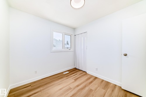 Bright interior space featuring wood-finish flooring, white walls, and a ceiling-mounted light fixture - 9D Castle Terrace, Edmonton, AB 