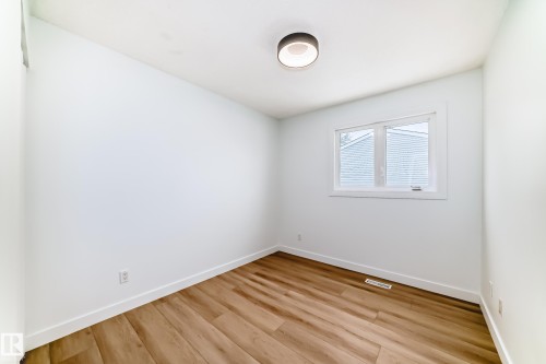 Bright room featuring wood-finish flooring, white baseboards, and a modern flush-mount ceiling light - 9D Castle Terrace, Edmonton, AB 