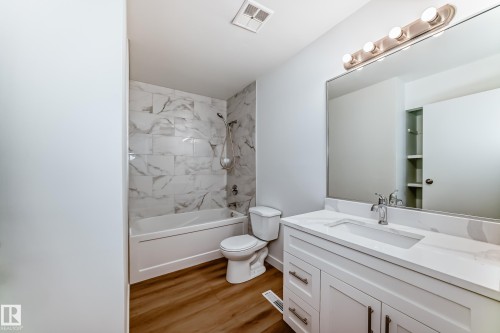 Bathroom featuring white shaker vanity with undermount sink, quartz countertop, and large mirror - 9D Castle Terrace, Edmonton, AB 