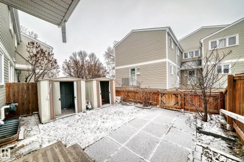 Enclosed patio space featuring two storage sheds, a wood privacy fence, and concrete paver pathways - 9D Castle Terrace, Edmonton, AB 