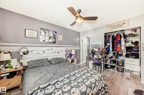 Bedroom featuring wood-finish flooring, a ceiling fan with integrated lighting, and a built-in closet with shelving and hanging space - 5106 19 Avenue, Edmonton, AB 