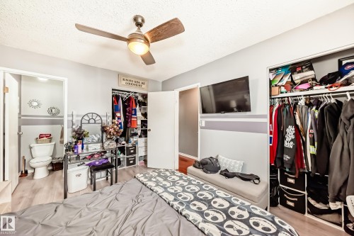 Room featuring light gray walls, wood-finish flooring, a ceiling fan with integrated lighting, and a closet with bifold doors - 5106 19 Avenue, Edmonton, AB 
