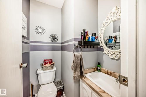 Compact bathroom featuring a white toilet, integrated sink with a light-toned countertop, and a white vanity cabinet - 5106 19 Avenue, Edmonton, AB 