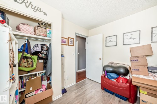 Room featuring wood-finish flooring, a built-in closet with shelving and hanging rod, and a white interior door - 5106 19 Avenue, Edmonton, AB 