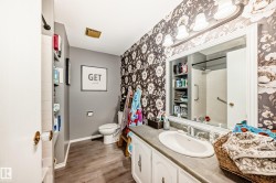 Bathroom featuring wood-finish flooring, a vanity with an integrated sink, and floral-patterned wallpaper - 