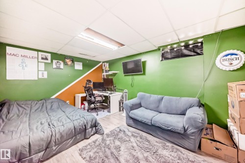 Room featuring wood-finish flooring, a drop ceiling, and a distinct two-tone wall design with an orange and green color scheme - 5106 19 Avenue, Edmonton, AB 