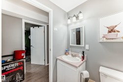 Bathroom featuring a white vanity cabinet with an integrated sink and light-toned countertop, a wall-mounted mirror, and a three-light fixture - 