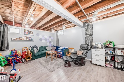 Finished basement area featuring wood-finish flooring, exposed ceiling joists, recessed lighting, and painted walls - 5106 19 Avenue, Edmonton, AB 