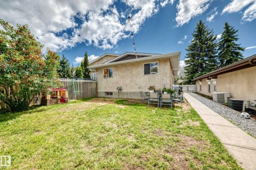 Spacious rear yard with a concrete patio, mature trees, and an established lawn area - 5106 19 Avenue, Edmonton, AB 
