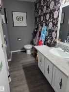 Bathroom featuring a vanity with white cabinetry, a single basin sink, and a gray countertop - 
