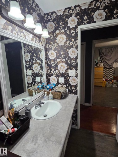 Bathroom vanity with a textured gray countertop and an integrated white oval sink - 5106 19 Avenue, Edmonton, AB 