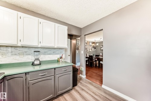 Kitchen featuring two-tone cabinetry with white upper and gray lower cabinets, a light green countertop, and a white mosaic tile backsplash - 5106 19 Avenue, Edmonton, AB 