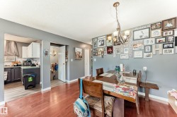 Dining area featuring wood-finish flooring, a decorative chandelier, and a framed opening to the kitchen - 