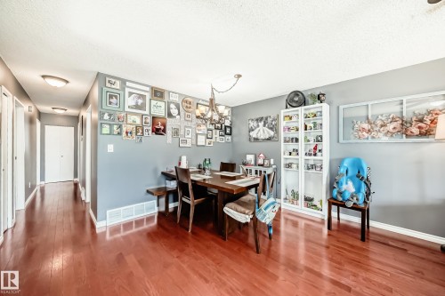 Dining area featuring wood-finish flooring, a contemporary chandelier, and a built-in white display cabinet - 5106 19 Avenue, Edmonton, AB 