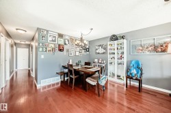 Dining area featuring wood-finish flooring, a contemporary chandelier, and a built-in white display cabinet - 