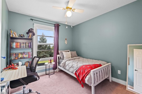 Bright room featuring a window with exterior views, light-colored walls, and a ceiling fan with integrated lighting - 12128 25 Avenue, Edmonton, AB - Indoor Photo Showing Bedroom