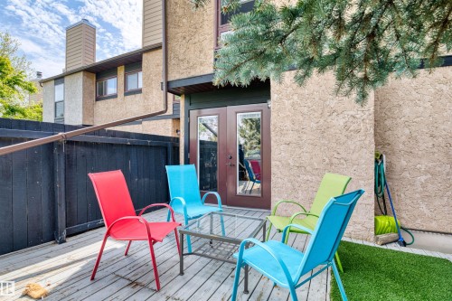 Wood-finish decking with a dark privacy fence and direct entry via a glass-paneled door - 12128 25 Avenue, Edmonton, AB - Outdoor With Deck Patio Veranda With Exterior