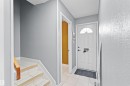 Entryway featuring a white paneled door with an arched transom window, ceramic tile flooring, and a stairway with wood-finish treads and a wood handrail - 12128 25 Avenue, Edmonton, AB  - Indoor Photo Showing Other Room 