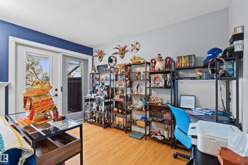 Room featuring wood-finish flooring, a vibrant accent wall, and built-in shelving - 12128 25 Avenue, Edmonton, AB - Indoor