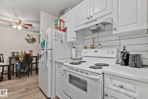 Kitchen featuring white cabinetry, white countertops, white electric range, white refrigerator, and a white shiplap-style backsplash - 115 4608 52 Avenue, Stony Plain, AB 