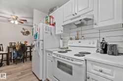 Kitchen featuring white cabinetry, white countertops, white electric range, white refrigerator, and a white shiplap-style backsplash - 