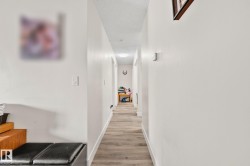 Long hallway featuring wood-finish flooring, white painted walls, and recessed lighting - 