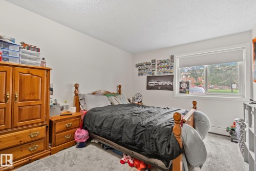Bright bedroom featuring a large window, plush gray carpeting, and white walls - 115 4608 52 Avenue, Stony Plain, AB 