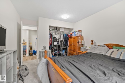 Bedroom featuring light gray carpeting, neutral wall paint, and a white ceiling with flush-mount lighting - 115 4608 52 Avenue, Stony Plain, AB 