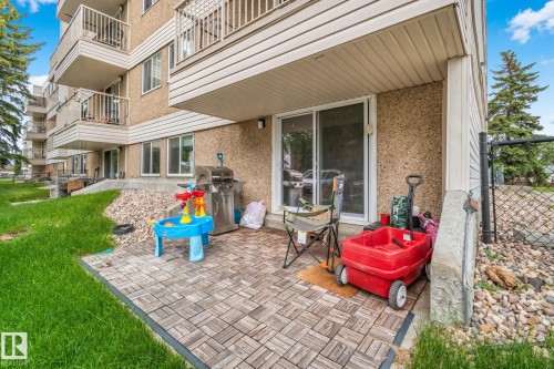 Ground-level patio featuring wood-finish paver tiles and direct access via sliding glass doors - 115 4608 52 Avenue, Stony Plain, AB 