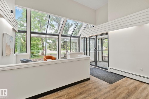 Two-story atrium featuring a vaulted glass ceiling, full-height windows, a glass entry door system, and wood-finish flooring - 115 4608 52 Avenue, Stony Plain, AB 