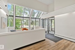 Two-story atrium featuring a vaulted glass ceiling, full-height windows, a glass entry door system, and wood-finish flooring - 