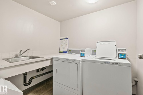 Laundry area featuring a utility sink, light-toned countertop, and two large-capacity washing machines - 115 4608 52 Avenue, Stony Plain, AB 