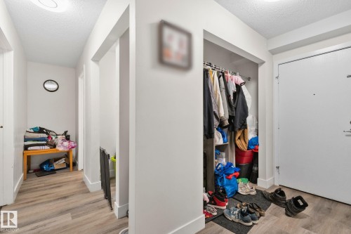 Entryway featuring a built-in closet with hanging rod, wood-finish flooring, white walls, and a flush-mount ceiling light - 115 4608 52 Avenue, Stony Plain, AB 