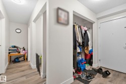 Entryway featuring a built-in closet with hanging rod, wood-finish flooring, white walls, and a flush-mount ceiling light - 