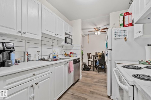 Kitchen featuring white cabinetry, a single basin stainless steel sink, a dishwasher, a microwave, and a white refrigerator - 115 4608 52 Avenue, Stony Plain, AB 