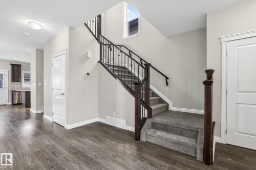 Staircase featuring dark wood newel posts and handrails with black metal balusters - 6927 Cardinal Wynd, Edmonton, AB 