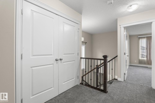 Hallway featuring white panel doors, neutral wall paint, and grey carpeting - 6927 Cardinal Wynd, Edmonton, AB 