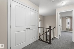 Hallway featuring white panel doors, neutral wall paint, and grey carpeting - 