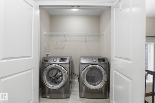 Dedicated laundry area with front-loading washer and dryer, featuring overhead wire shelving and light-toned flooring - 6927 Cardinal Wynd, Edmonton, AB 
