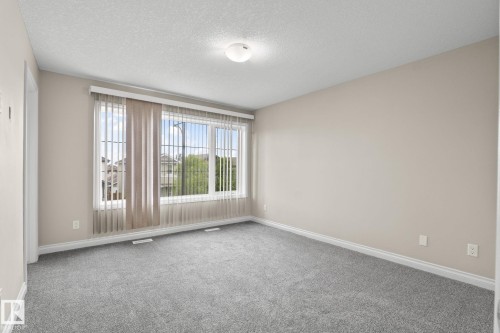 Spacious room featuring neutral carpeting, light-toned wall paint, and white trim - 6927 Cardinal Wynd, Edmonton, AB 