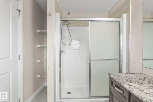 Shower with sliding frosted glass doors, chrome fixtures, and white acrylic surround - 6927 Cardinal Wynd, Edmonton, AB 