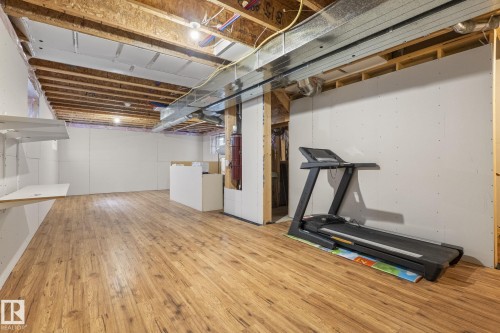 Finished lower level featuring wood-finish flooring, exposed ceiling joists, and partial drywall - 6927 Cardinal Wynd, Edmonton, AB 