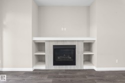 Fireplace feature wall with integrated shelving, tile surround, and wood-finish flooring - 