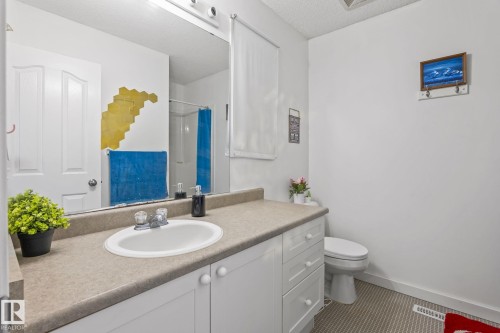 Bathroom featuring a white vanity with an integrated sink, a neutral-toned countertop, and a large wall-mounted mirror - 128 Brookview Wy, Stony Plain, AB 