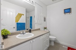 Bathroom featuring a white vanity with an integrated sink, a neutral-toned countertop, and a large wall-mounted mirror - 