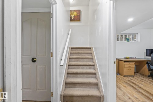 Carpeted staircase with white handrail and trim, leading to a space with wood-finish flooring and a horizontal window - 128 Brookview Wy, Stony Plain, AB 