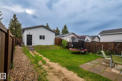 Detached accessory building with light-colored siding, black entry door, and a shingled roof - 128 Brookview Wy, Stony Plain, AB 