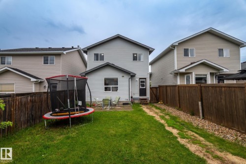 Expansive backyard featuring a lush lawn, wood fencing, and a concrete patio - 128 Brookview Wy, Stony Plain, AB 