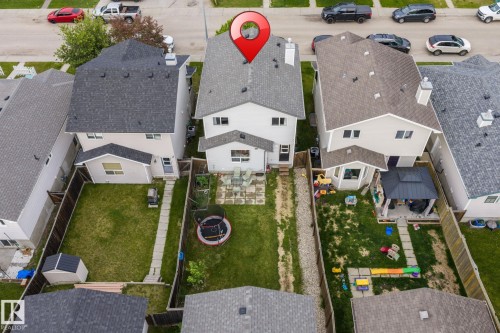 Expansive fenced backyard featuring a manicured lawn, stone patio, and detached storage shed - 128 Brookview Wy, Stony Plain, AB 