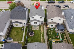 Expansive fenced backyard featuring a manicured lawn, stone patio, and detached storage shed - 